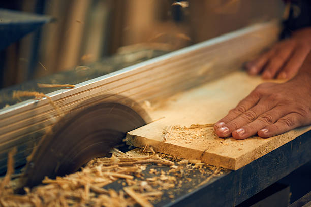 Professional carpenter using circular saw in his carpentry workshop. Focus on a saw