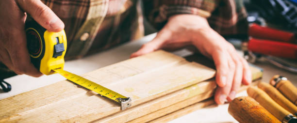 Carpenter holding a measure tape on the work bench